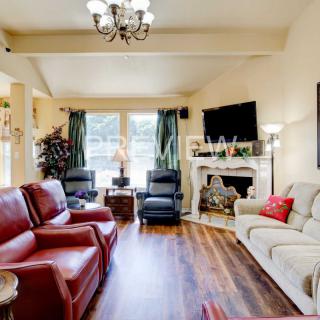 A spacious living room with comfortable seating, a fireplace, and a mounted television.