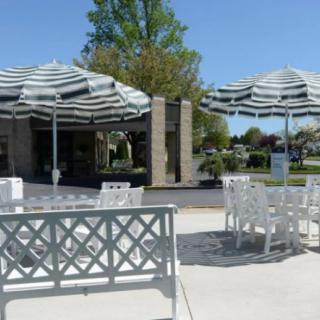A sunny outdoor patio with white tables and chairs under striped umbrellas.