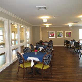 A neatly arranged dining room with round tables and patterned chairs.