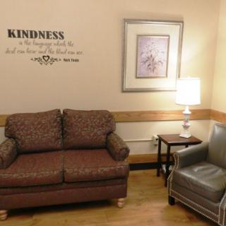 A cozy living space featuring a couch, chair, and a lamp with wall art and an inspirational quote.