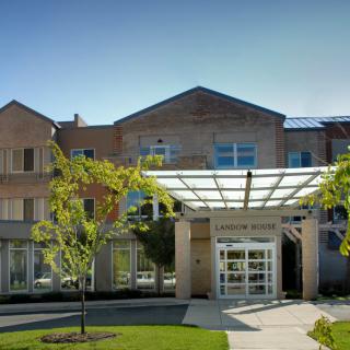 A modern building with a glass-covered entrance surrounded by trees.