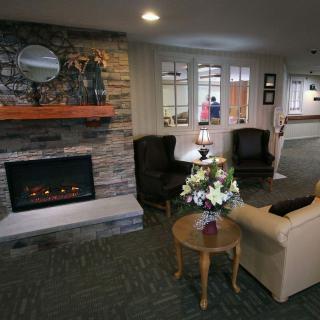 A cozy living room area with a fireplace, comfortable seating, and a coffee table with flowers.