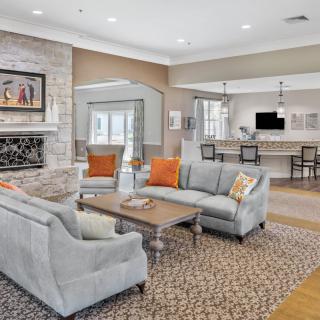 A modern living room with an open concept design, featuring comfortable sofas, a coffee table, and a fireplace, leading to a kitchen area.
