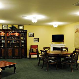 A cozy living room with a dining table, cabinet, and television, adorned with artwork.