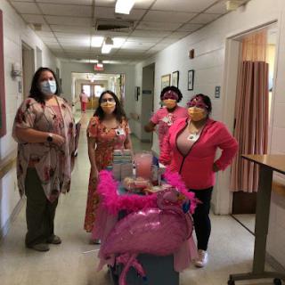 Healthcare workers celebrating in a hospital hallway, adorned in pink attire.