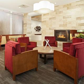 A modern lounge area featuring red chairs and a fireplace.