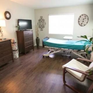 A neatly arranged room with a bed, television, and decor.
