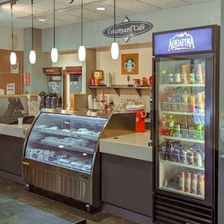 A cozy cafe interior featuring a food display case and a beverage cooler.