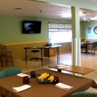 A cozy indoor dining area with tables set for meals and a television mounted on the wall.