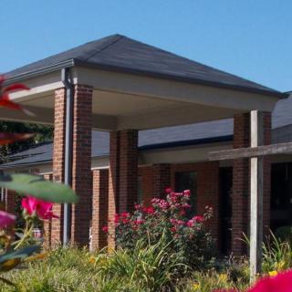 A brick building with a sloped roof surrounded by a garden with vibrant flowers.
