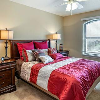 A cozy bedroom with red bedding and elegant decor.