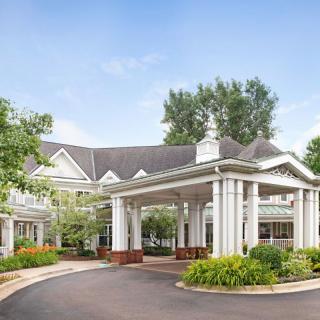 A grand building entrance with columns, surrounded by lush landscaping and trees.