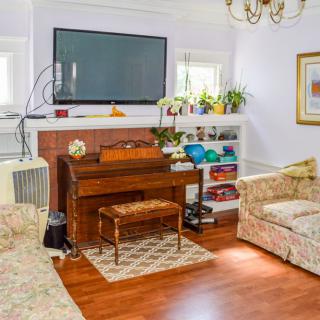 A cozy living room featuring a piano, television, and comfortable seating.