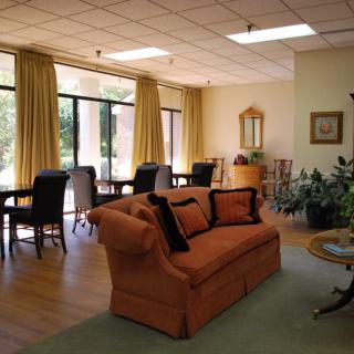 A cozy living room with a sofa, chairs, and large windows adorned with curtains.
