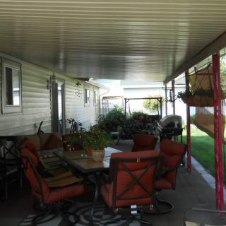 A covered patio with comfortable outdoor seating and green plants.