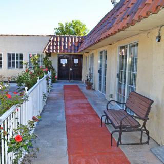A quaint outdoor walkway with a bench and blooming flowers lining the path.