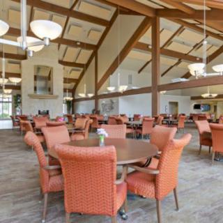 Spacious dining hall with wooden beams and orange chairs.