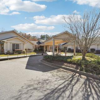 A view of residential buildings with a driveway and landscaped surroundings on a sunny day.