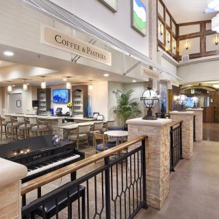 A spacious hotel lobby with a piano and modern seating area, featuring bright lighting and stylish decor.