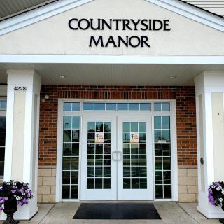The entrance to Countryside Manor with large glass doors and a sign above.