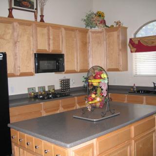 A modern kitchen featuring wooden cabinets, a sleek countertop, and a decorative fruit basket.