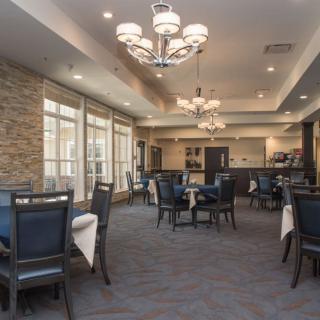 A modern dining room with elegant chandeliers and neatly arranged tables and chairs.
