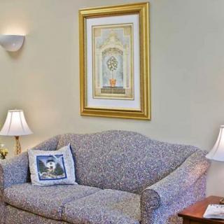 A cozy living room with a patterned couch, decorative cushions, framed wall art, and ambient lighting.