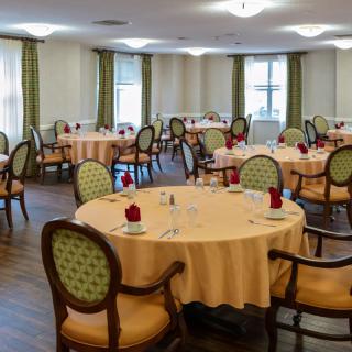 An elegant dining room with round tables and chairs, set for a meal.