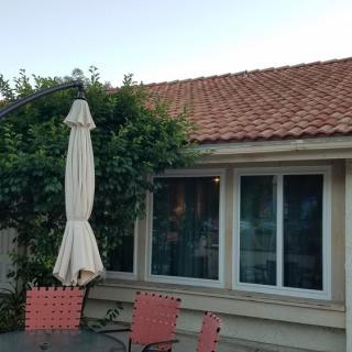 A cozy patio setup with chairs and an umbrella in front of a house with tiled roofing.