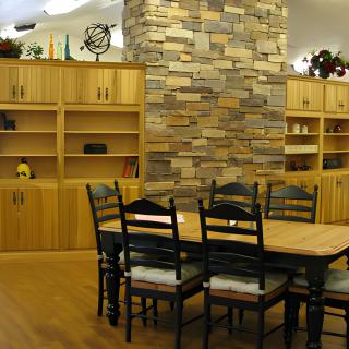 A cozy dining room with wooden furniture and a stone accent wall.