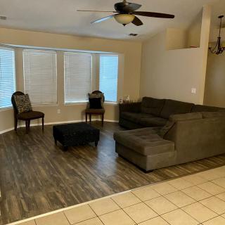 A spacious living room featuring a large sectional sofa, two chairs, and a ceiling fan above a hardwood floor.