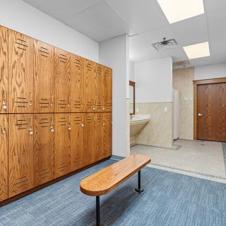 A clean and organized locker room with wooden lockers and a bench.