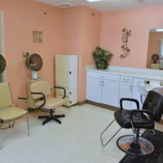 A cozy hair salon interior with chairs, a mirror, and hair dryers.