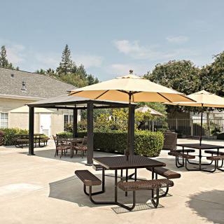 A sunny outdoor patio area with picnic tables and umbrellas.