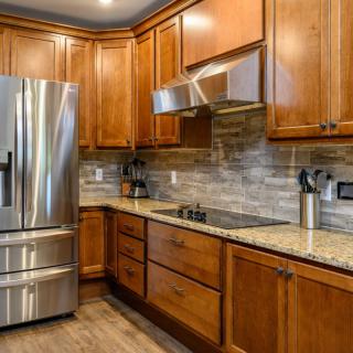 A modern kitchen featuring stainless steel appliances, wooden cabinets, and a granite countertop.