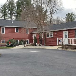 A suburban brick house with a driveway and surrounding trees.