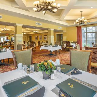 An elegant dining room with neatly arranged tables and chairs, featuring chandeliers and tasteful decor.