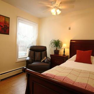 A cozy bedroom with a wooden bed frame, comfortable chair, and a warm lamp illuminating the space.
