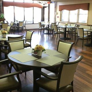 An empty dining area with neatly arranged tables and chairs on a wooden floor.