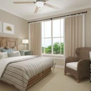 A cozy bedroom with a large bed, armchair, and natural lighting from a big window.