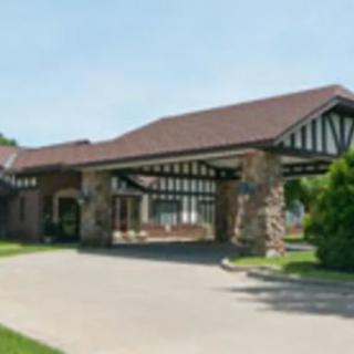 A building with a covered entrance and stone pillars surrounded by greenery.