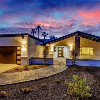 A modern house with a beautifully landscaped driveway at sunset.