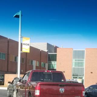 A red truck parked in front of a modern building under a clear blue sky.