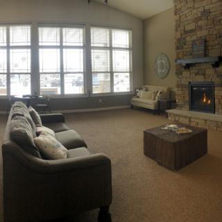 A cozy living room with a sofa, fireplace, and large windows.
