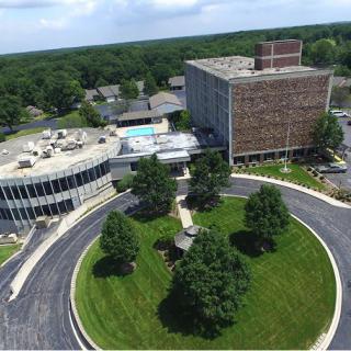 Aerial view of a modern office building with a circular driveway and landscaped surroundings.