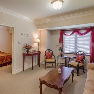 A cozy living room with a sofa and chairs arranged around a wooden coffee table, featuring stylish decor and curtains on the window.