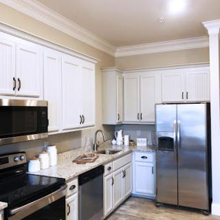 A modern kitchen featuring sleek white cabinetry and stainless steel appliances.