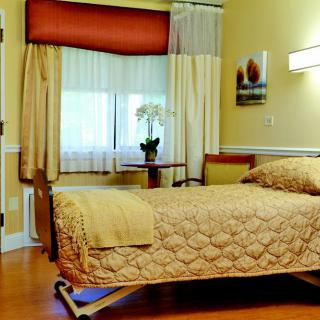 A well-furnished hospital room with a single bed and natural lighting.