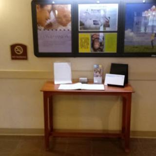 A small wooden table displaying informational materials in a lobby area.