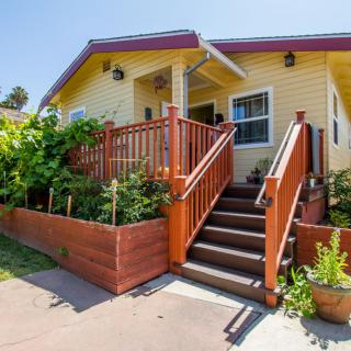 A charming yellow house with a welcoming front porch and landscaped garden.
